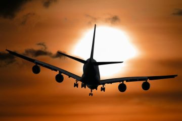 Dramatic silhouette of an airplane flying against a vibrant sunset sky.
