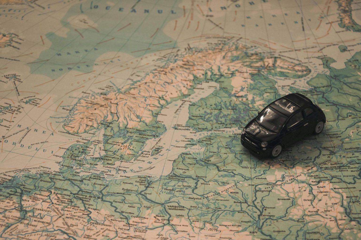 Transformarea pieței europene de traduceri : între inovație și provocări A miniature black car on a detailed map of Scandinavia, symbolizing travel adventures.